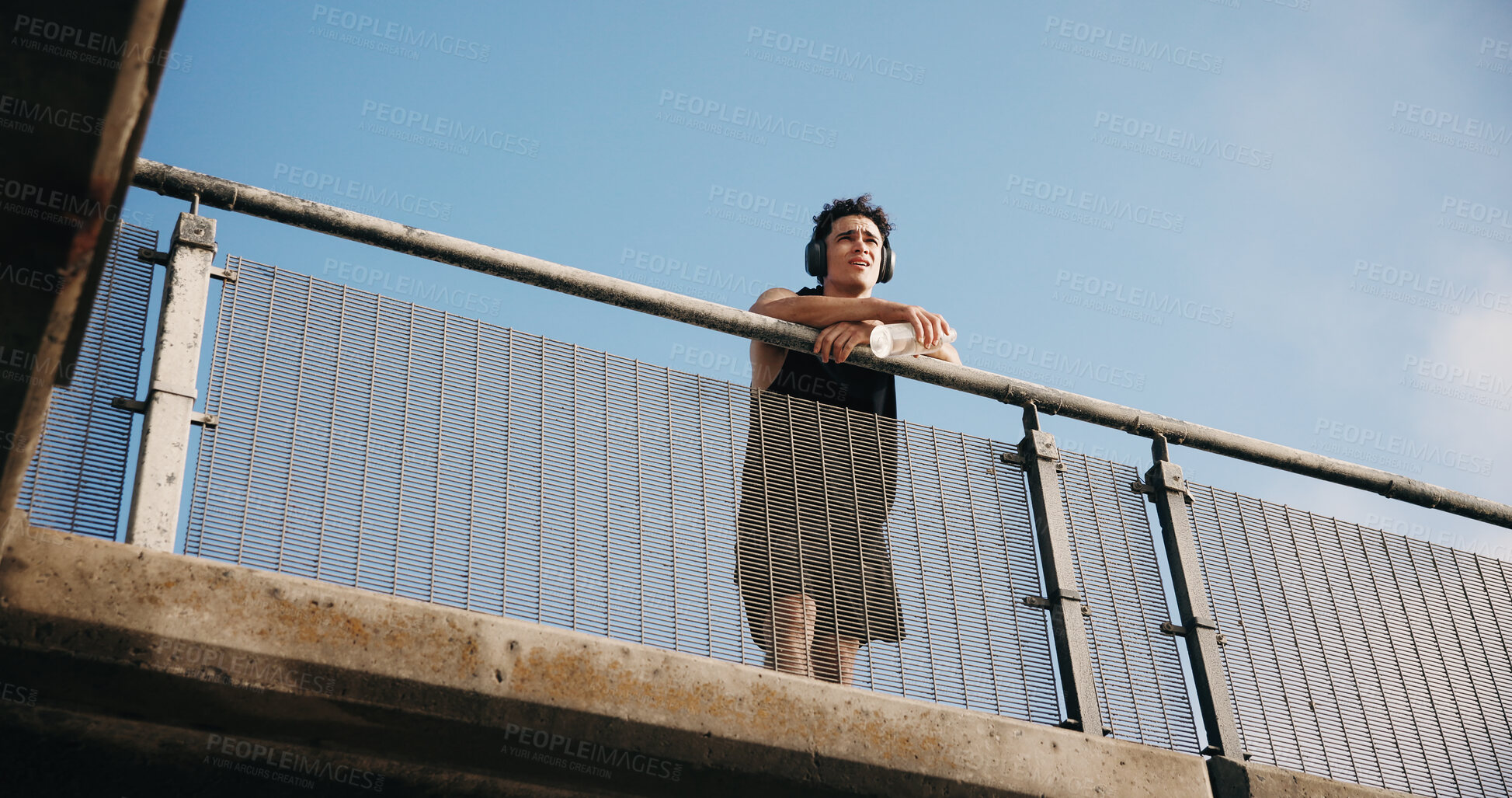 Buy stock photo Athlete, thinking and man with headphones on bridge, wonder or memory of training with music playlist. Outdoor, low angle and person with audio tech, pace and reflection after exercise and health