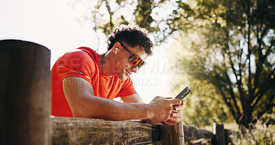 Buy stock photo Fitness, earphones and man in nature with phone for social media after training, exercise and break. Sports, athlete and person on smartphone for health app, internet and streaming music outdoor