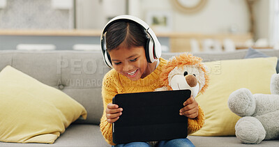 Buy stock photo Child, tablet and watching movie in living room with headphones, plush toy and laugh for funny cartoon. Happy, girl and streaming show in house with audio tech, kids comedy or film for entertainment.