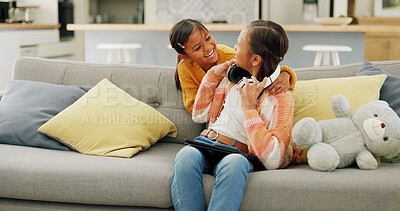 Buy stock photo Happy, laugh and sisters with tablet on sofa for bonding, playful relationship and entertainment in home. Family, siblings and kids with tech, headphones and online videos to relax in living room
