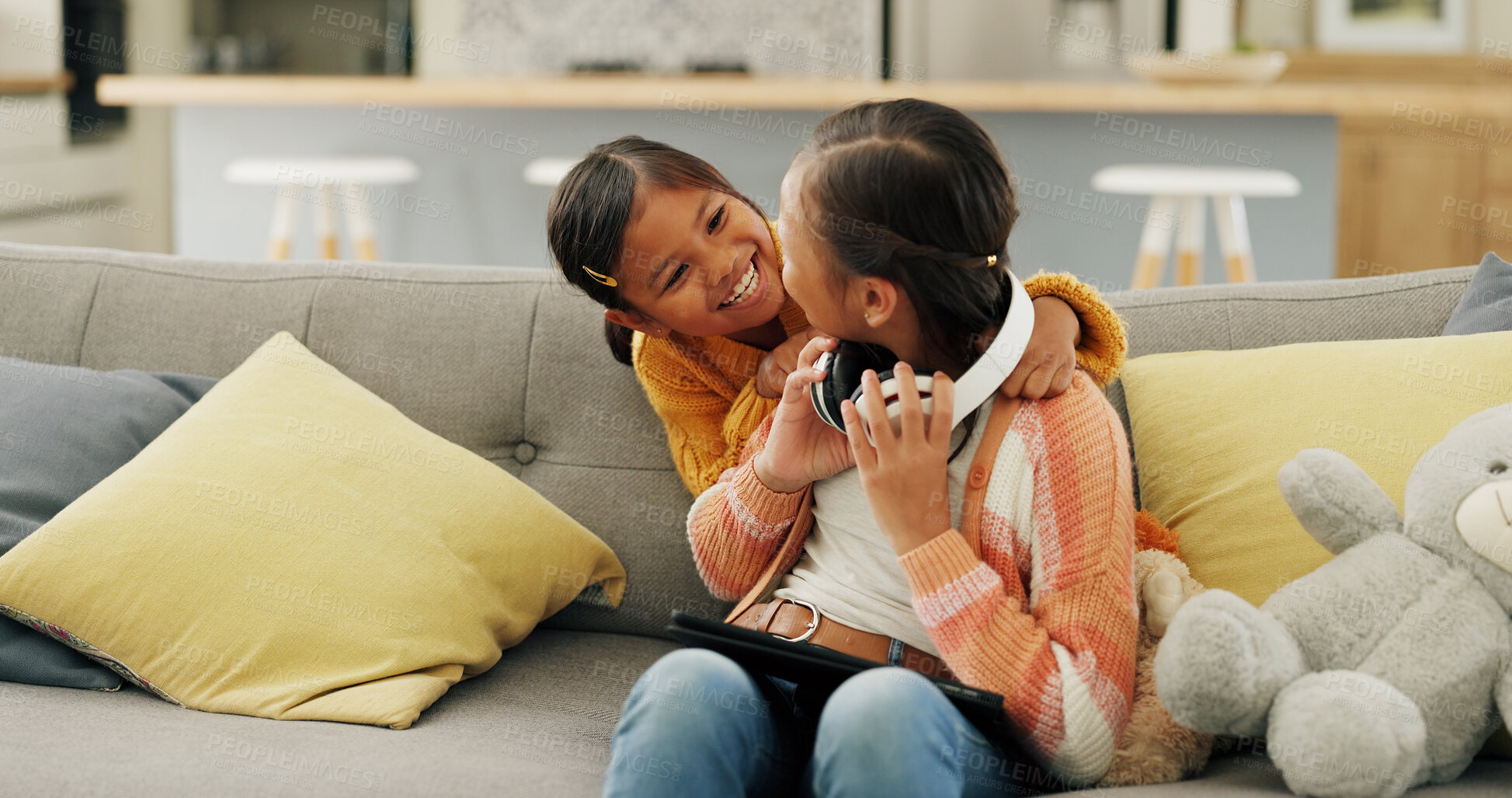 Buy stock photo Happy, sisters and children with tablet on sofa for bonding, playful relationship and entertainment in home. Family, siblings and girls with tech, headphones and online videos to relax in living room