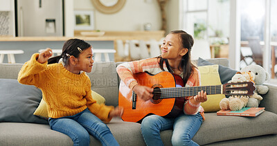 Buy stock photo Girl, guitar and happy in home with sister for dancing, music and bonding with love on sofa in lounge. Kids, smile and play song with instrument, sound and creativity in living room at family house