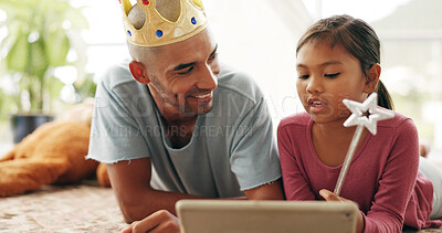 Buy stock photo Education, smile and tablet of daughter with dad on living room floor for family or fantasy story. App, crown and wand of girl child with single parent man in apartment for learning or streaming