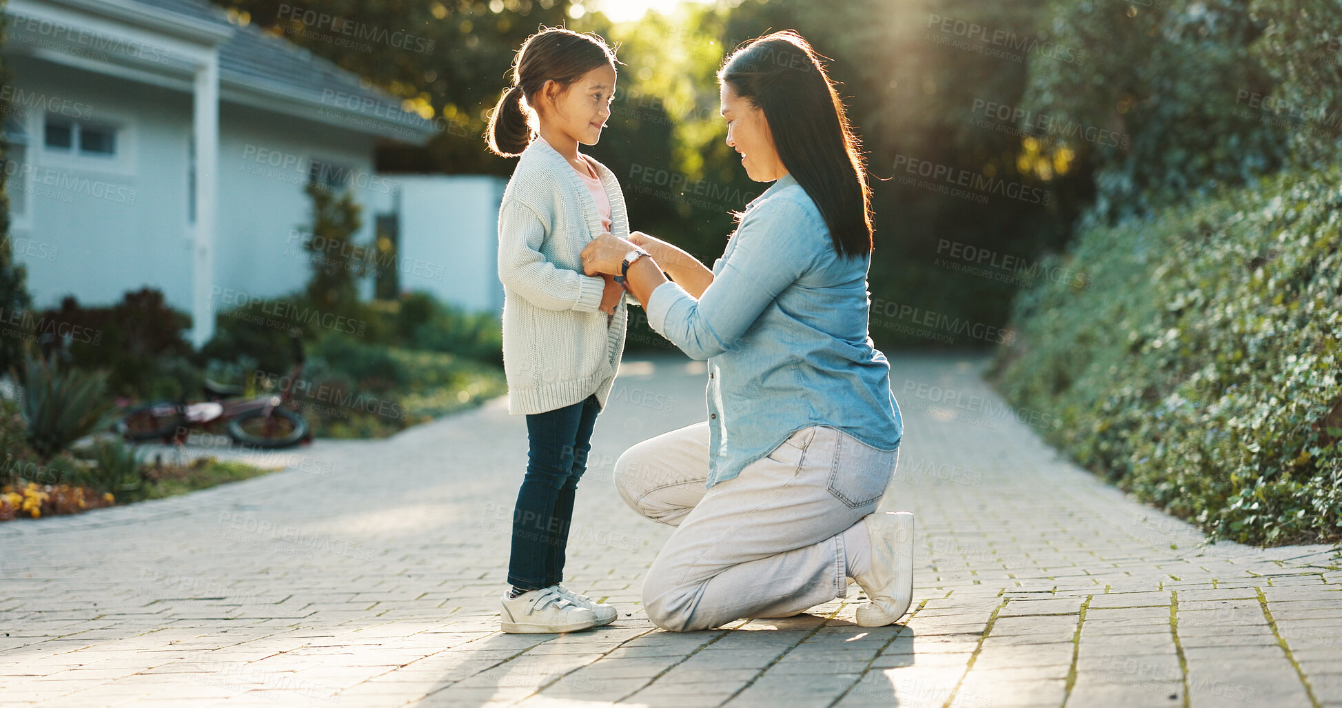 Buy stock photo Child, mother and help with button at backyard, smile and bonding together for development by house. Mom, girl and assistance with clothes change, growth and love of parent outdoor with happiness