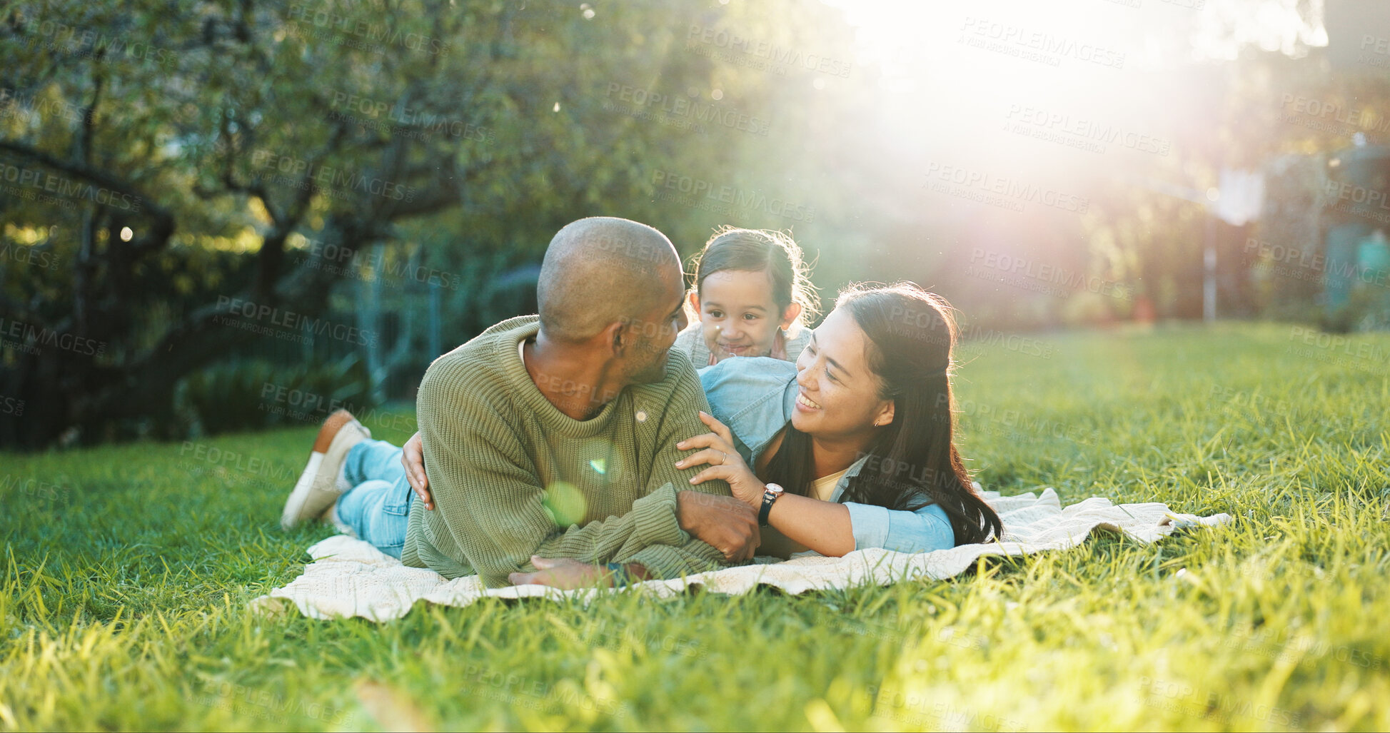 Buy stock photo Happy, parents and relax on picnic blanket with child, support and bonding together on weekend break. Mother, father and people outdoor in nature with daughter, flare and love for family connection.