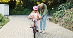 Balance, push and father teaching daughter how to ride bicycle outdoor in front of home. Help, protection and safety of girl child with single parent man in driveway for cycling activity or learning