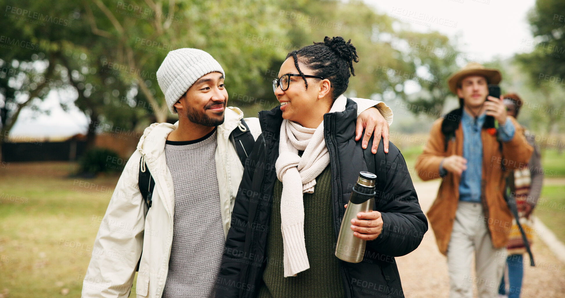 Buy stock photo Couple, hiking and happy with embrace at park with group, outdoor and bonding on vacation in winter. People, walk and trekking with smile, love and connection with care on holiday for nature tourism