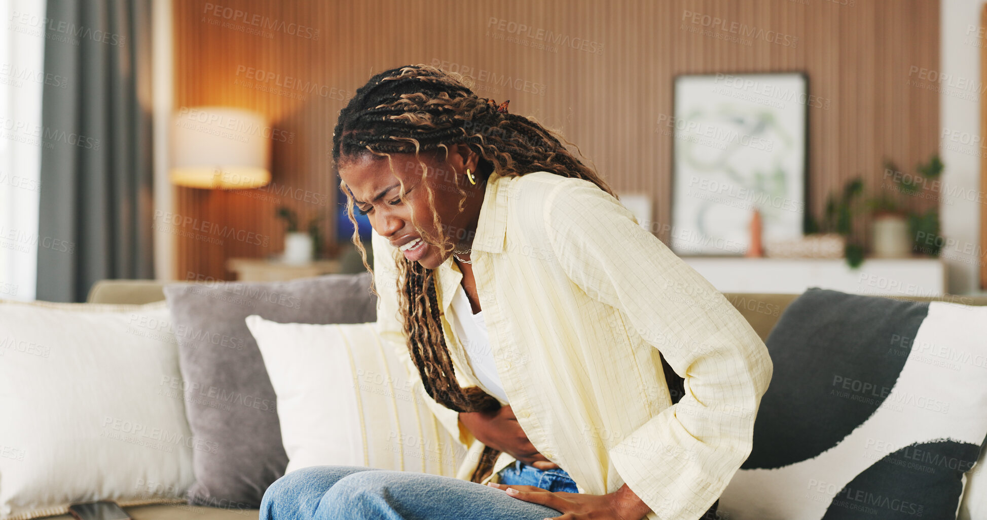 Buy stock photo Stress, pain and woman with stomach ache on sofa for menstruation, constipation or PMS. Endometriosis cramps, black girl or belly indigestion in home from ovulation cycle, IBS or abdominal discomfort