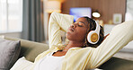 Black woman, headphones and relax with rest on sofa, eyes closed and break for streaming service in home. African person, chill and listen to music with audio, sound or subscription on couch at house
