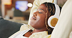 Black woman, headphones and relax with rest on couch, eyes closed and break for streaming service in home. African person, chill and listen to music with audio, sound or subscription on sofa at house