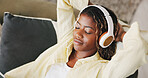 Black woman, headphones and relax with break on sofa, eyes closed and rest for streaming service in home. African person, chill and listen to music with audio, sound or subscription on couch at house