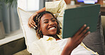 Funny, home and black woman on sofa, tablet for social media and reaction for post. Happy, tech and African person on couch, connection for online announcement and laughing for comedy video or joke