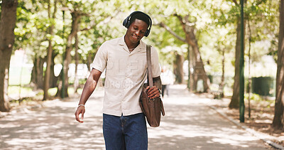 Buy stock photo Black man, walk and happy at park with headphones, streaming or listen to music on commute in summer. African person, smile and inspiration with bag for travel, sound or audio subscription in town