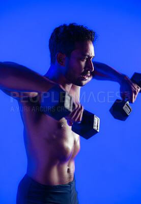 Buy stock photo Man, dumbbells and fitness with weightlifting in studio with power, muscle and training on blue background. Person, bodybuilder and strong with exercise challenge, shirtless or workout with equipment