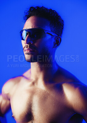 Buy stock photo Man, sunglasses and shirtless in studio with fitness, bodybuilding and muscle growth on blue background. Person, shades and strong with glow, sweaty and transformation for wellness with healthy body