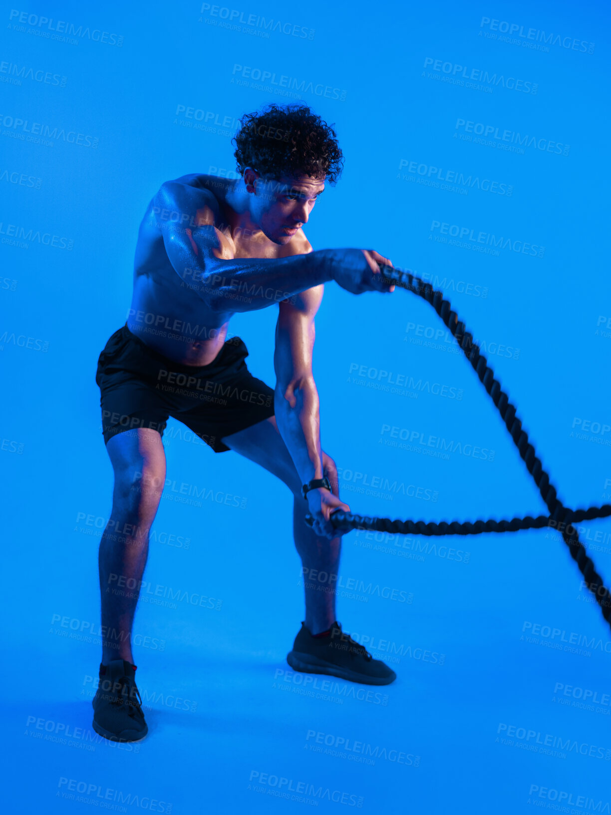 Buy stock photo Man, battle rope and exercise in studio for training, muscle and challenge on blue background. Person, cord and sweat with intense workout, fitness and power with endurance for cardio wellness