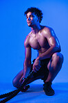 Man, battle rope and tired in studio for training, muscle and thinking with break on purple background. Person, rest and sweat with workout, exercise and cord with perspective for cardio wellness