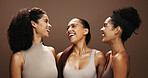 Women, laugh and skincare in studio with makeup, bonding together or cosmetics for beauty aesthetic. Happy, female friends and dermatology for glowing skin, wellness or solidarity on brown background