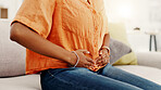 Hands, cramps and woman with stomach pain in home for sore abdomen and menstruation. Period, uncomfortable and person with pms, menstrual discomfort and digestion for tummy ache in living room