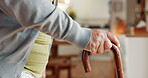 Senior, hands and walking with cane in home for mobility, old age assistance or recovery aid. Closeup, elderly or person with a disability or wooden stick for stability or support in retirement house