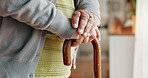 Elderly, person and hands with cane in home for mobility, old age assistance or walking aid. Closeup, senior or support with wooden stick for stability, safety or help in retirement or nursing house