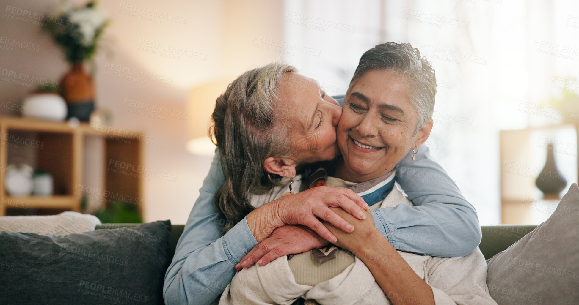 Buy stock photo Lesbian, cheek kiss or couple in house with hug, commitment or bonding together on weekend break. LGBTQ, happy or mature women with affection, connection or romantic moment in healthy relationship.