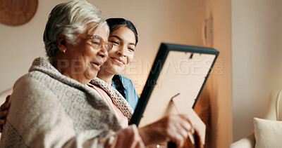 Buy stock photo Caregiver, talk and old woman in nursing home with picture frame, bonding and explain good memories. Happy, senior person and nurse in retirement center with photo, discussion and nostalgia for past.