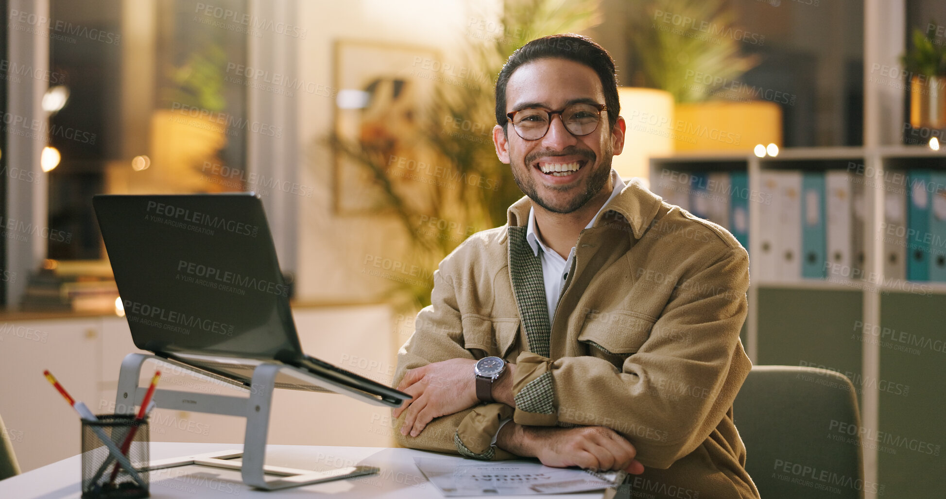 Buy stock photo Office, laptop and happy man with arms crossed at night, portrait or reporter with glasses for story. Newsroom, eyewear and person with smile for career growth, publishing and working late with tech