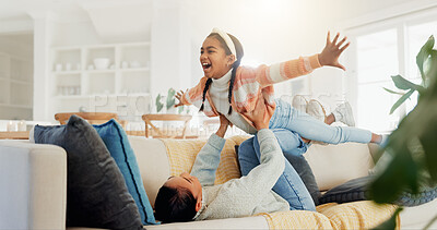 Buy stock photo Happy, mother and lift child on couch with support, trust and play for bonding together on weekend. Caring mom, young daughter and flying game in house with laugh, connection or love for development.