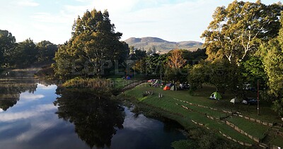 Buy stock photo Aerial, people and camping by lake with tent, tranquility and holiday destination for tourist trip. Outdoor, campsite and group by river for adventure, vacation and getaway for weekend in nature.