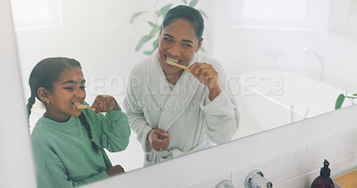 Buy stock photo Mom, child and brushing teeth with mirror in bathroom for dental hygiene, grooming or cleaning together. Mother, girl or daughter with smile or reflection for oral care or morning routine in home