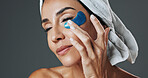 Eye patch, woman and skincare in studio for anti aging, confidence and aesthetic in dermatology. Mature person, treatment and towel with cosmetology, beauty or cosmetics with glow on gray background