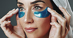 Woman, studio and skincare with eye patches for collagen or detox on a gray background. Female person, model or facial treatment with mask or pads for beauty cosmetics, anti aging or skin hydration
