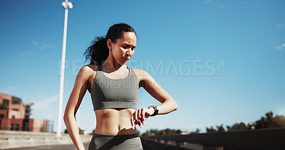 Buy stock photo City, runner and woman with watch for exercise progress, health app and fitness tracker outdoor. Sports, blue sky and person check time for training, workout and active hobby for wellness in town