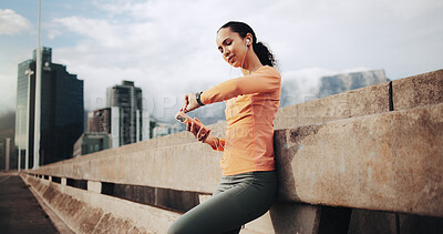 Buy stock photo Fitness, smart watch and woman in city with earphones, cardio info or streaming music with phone. Runner, person and check wristwatch on bridge for exercise stats, timer or listen to audio with tech