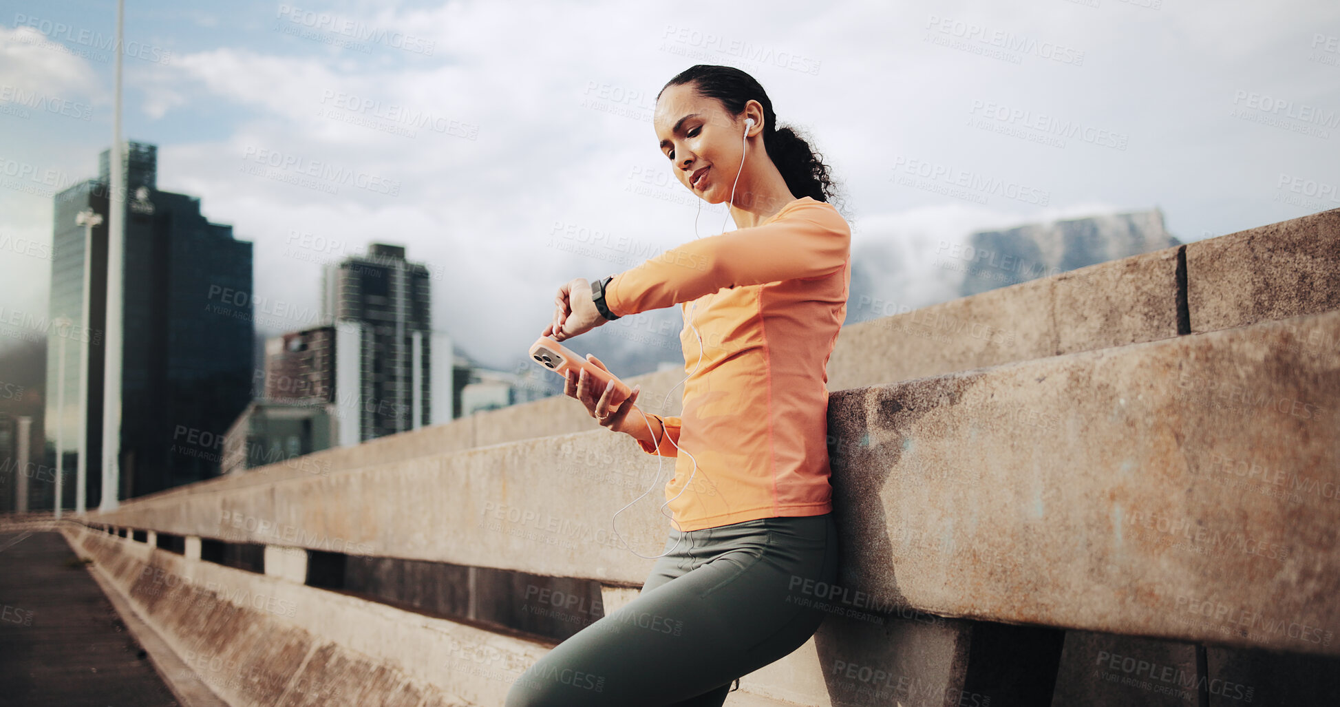 Buy stock photo Fitness, smart watch and woman in city with earphones, cardio info or streaming music with phone. Runner, person and check wristwatch on bridge for exercise stats, timer or listen to audio with tech