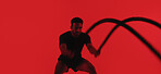 Man, fitness and battle rope in studio with exercise, strength training and intense physical activity. Mockup space, person and workout with endurance challenge, cardio or wellness on red background.