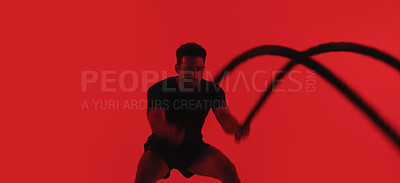 Buy stock photo Man, fitness and battle rope in studio with exercise, strength training and intense physical activity. Mockup space, person and workout with endurance challenge, cardio or wellness on red background