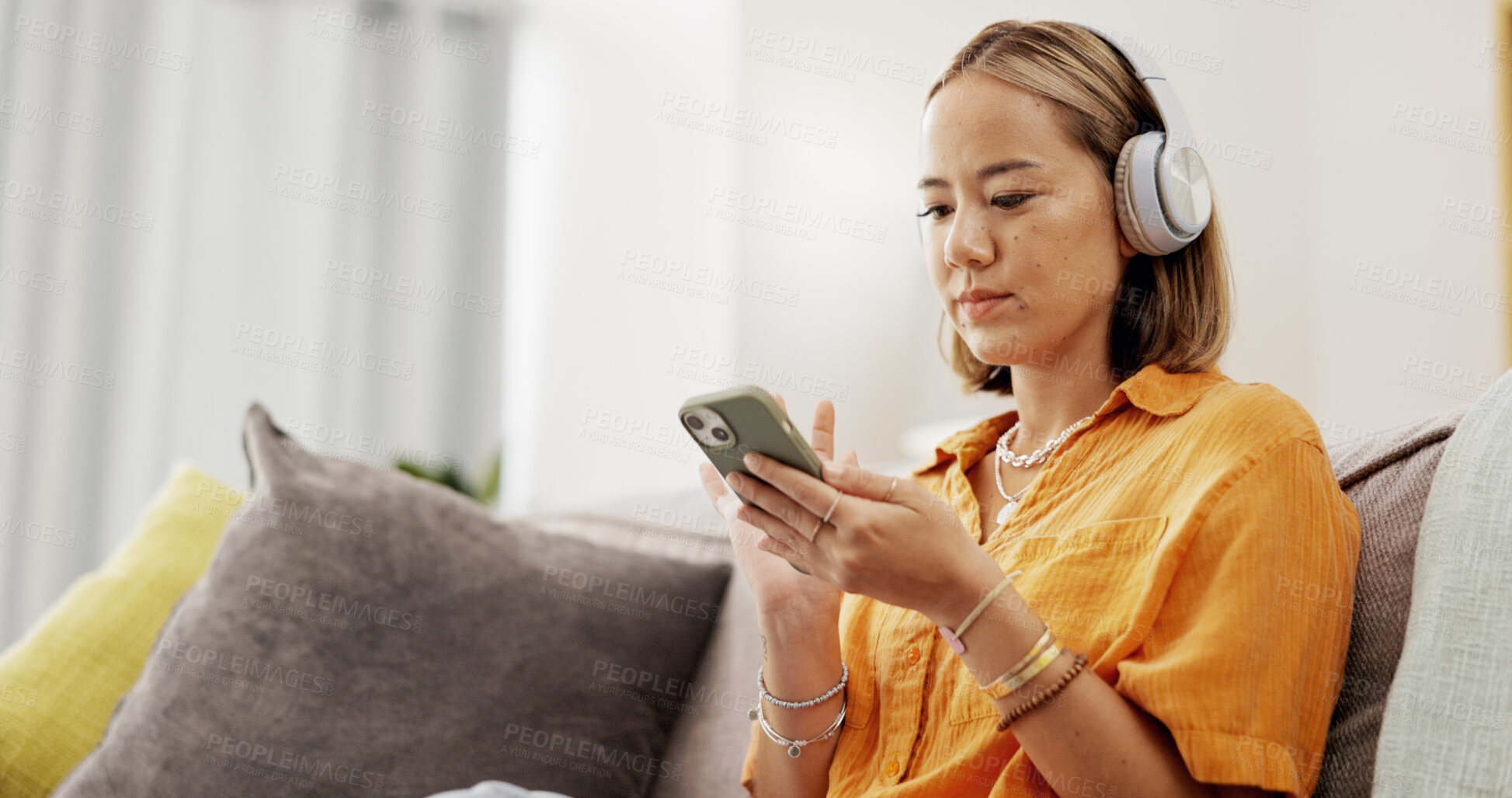 Buy stock photo Chill, phone or Asian woman in home with headphones, song connection or listening to music playlist. Relax, scroll or person in living room with tech, podcast or radio subscription on audio app.