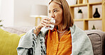Sick, water and woman on sofa in home with medicine for cold, flu or sinus infection in lounge. Illness, virus and female person drinking health beverage for allergies or hayfever in living room.