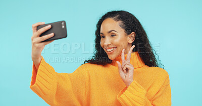 Buy stock photo Happy, peace sign and woman in studio with selfie for social media, online post and content creator. Smile, influencer and person with emoji for profile picture, photo and memory on blue background