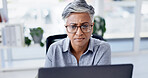 Serious, online and businesswoman with laptop in office, research and financial analysis on website. Business, bookkeeper and mature person with tech for tax preparation, glasses and reading on app