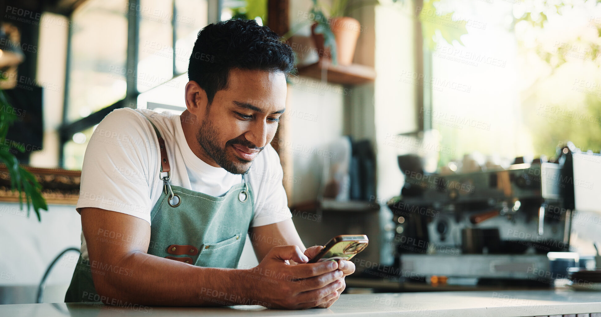 Buy stock photo Texting, smile and barista in cafe with phone, chat or social media update on work break. Message, mobile or man in restaurant with tech, small business review or online communication in coffee shop.