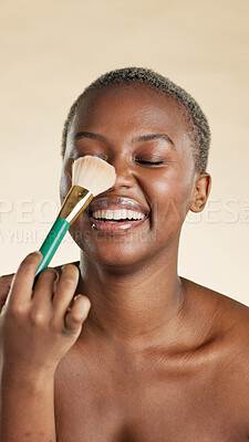Buy stock photo Black woman, beauty and laugh with makeup brush for self care, powder and coverage product. Facial, glow and tool on studio background for wellness, dermatology and happy for foundation or contour