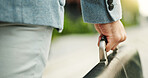 Person, hands and travel with briefcase for business journey, work trip or start career on sidewalk. Businessman, traveler or carrying handle with bag for outdoor job opportunity or urban commute