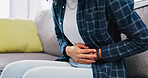 Woman, hands and sofa with stomach ache in home for menstruation, pain or period cramps. Female person, sore belly and indigestion with gastrointestinal reflux or discomfort for IBS or constipation