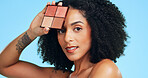 Beauty, portrait and woman with foundation palette to recommend cosmetics or makeup on blue background. Blusher, complexion and powder with person in studio for aesthetic change or transformation