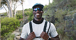 Portrait, hiking and happy man with glasses in woods, break or travel with hydration vest on holiday. Hiker, smile and black person with eyewear in nature, vacation and outdoor for adventure in Kenya