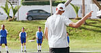 Coach, team and kids on field for sports, practice and help with football game play. Man, children and soccer match, training and exercise with youth athlete group at pitch for fitness outdoor