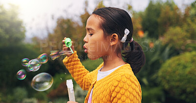Buy stock photo Outdoor, child and blowing bubbles in nature, growth and development with activity on weekend break. Park, entertainment and girl with toy for soap balloons, fine motor skills or playing game for fun